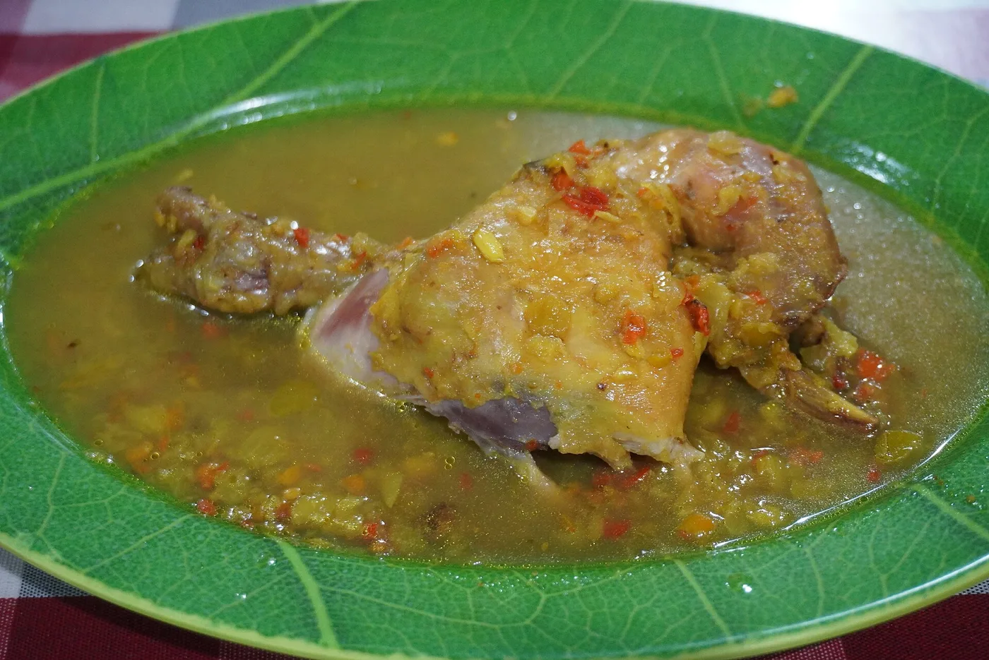 A plate of ayam betutu — Balinese chicken slow-cooked in spice paste — in its broth