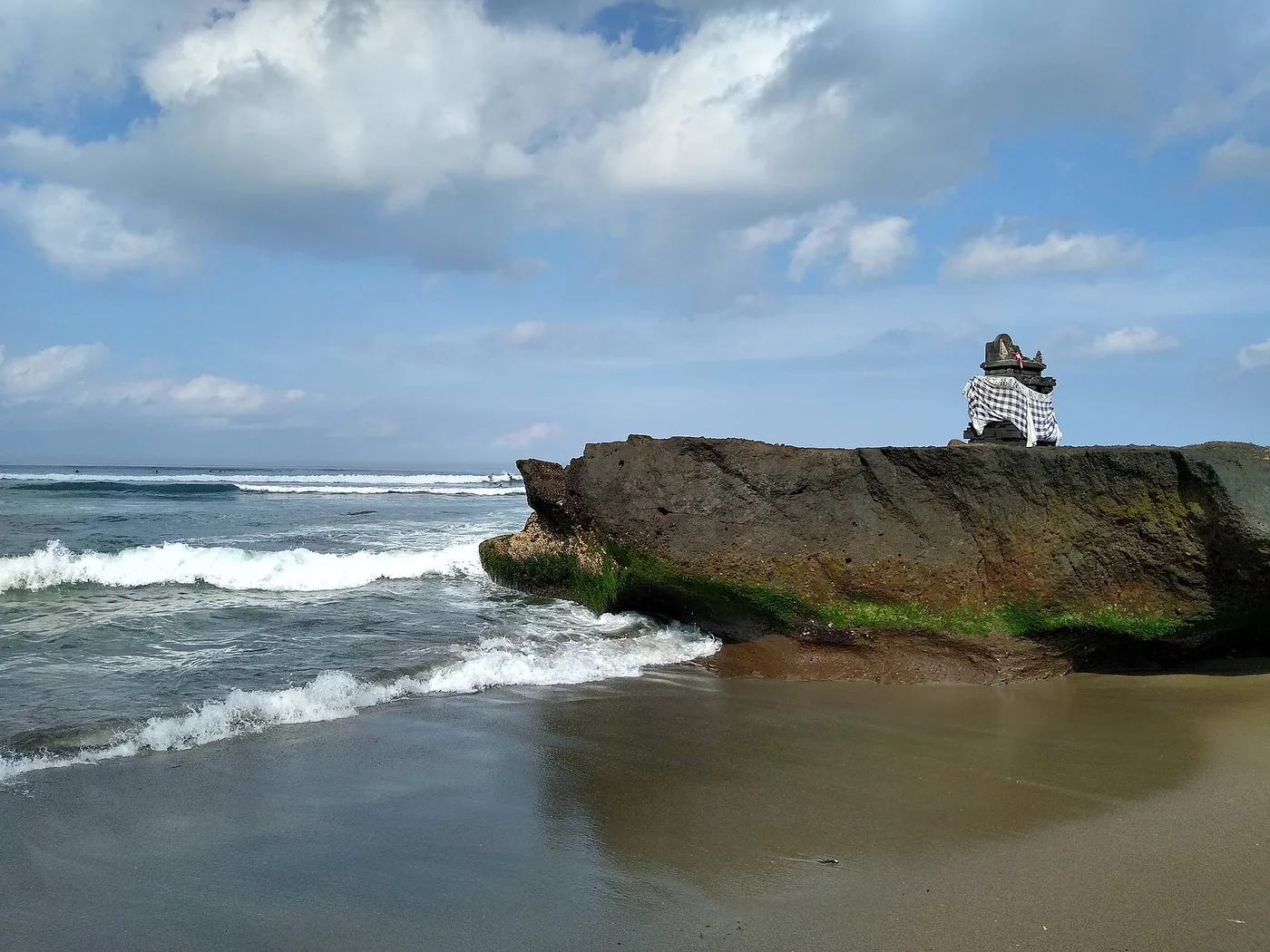 The dark-sand surf beach at Canggu with a small clifftop shrine