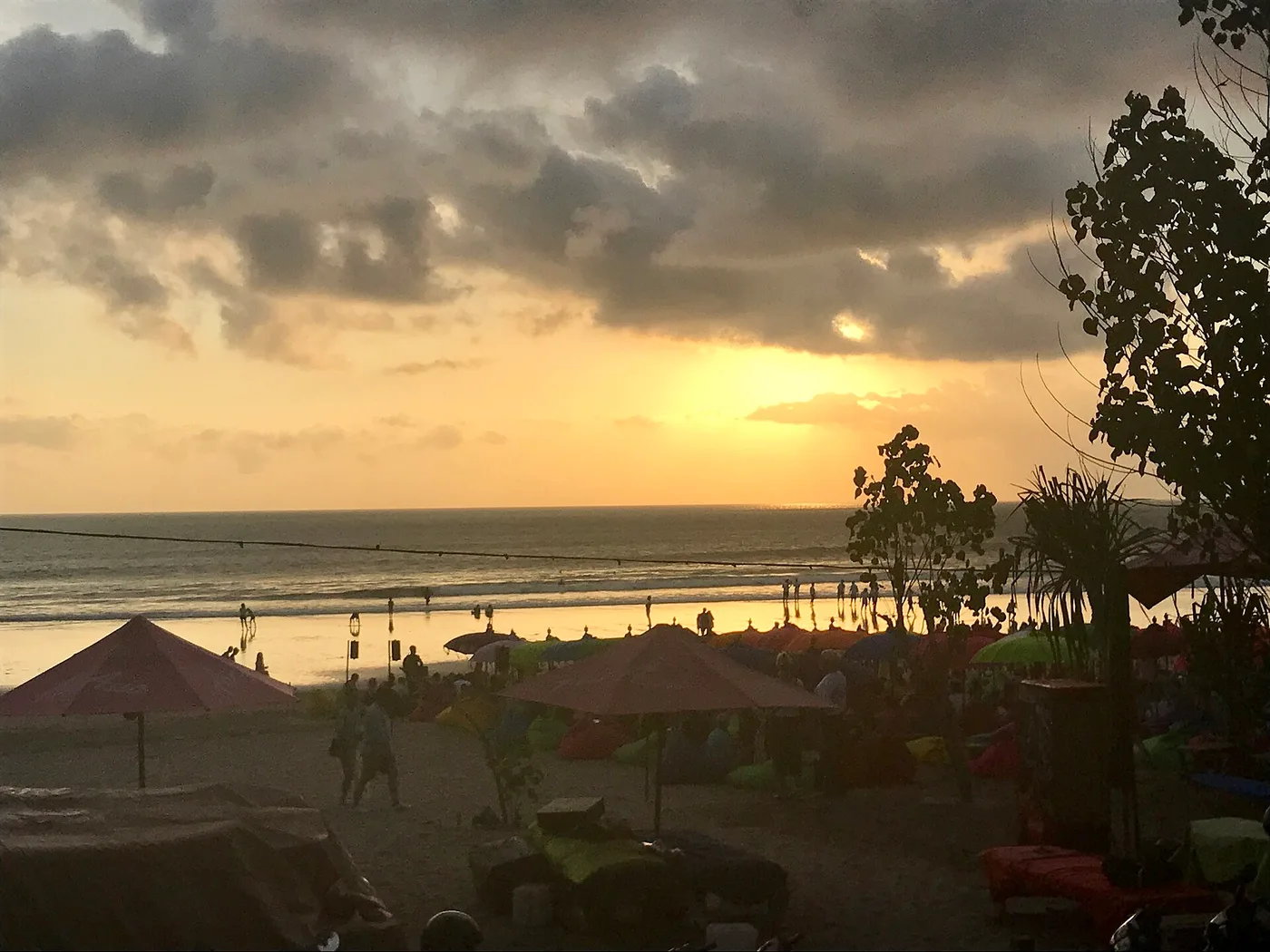Sunset over Seminyak beach with umbrellas and beanbags on the sand