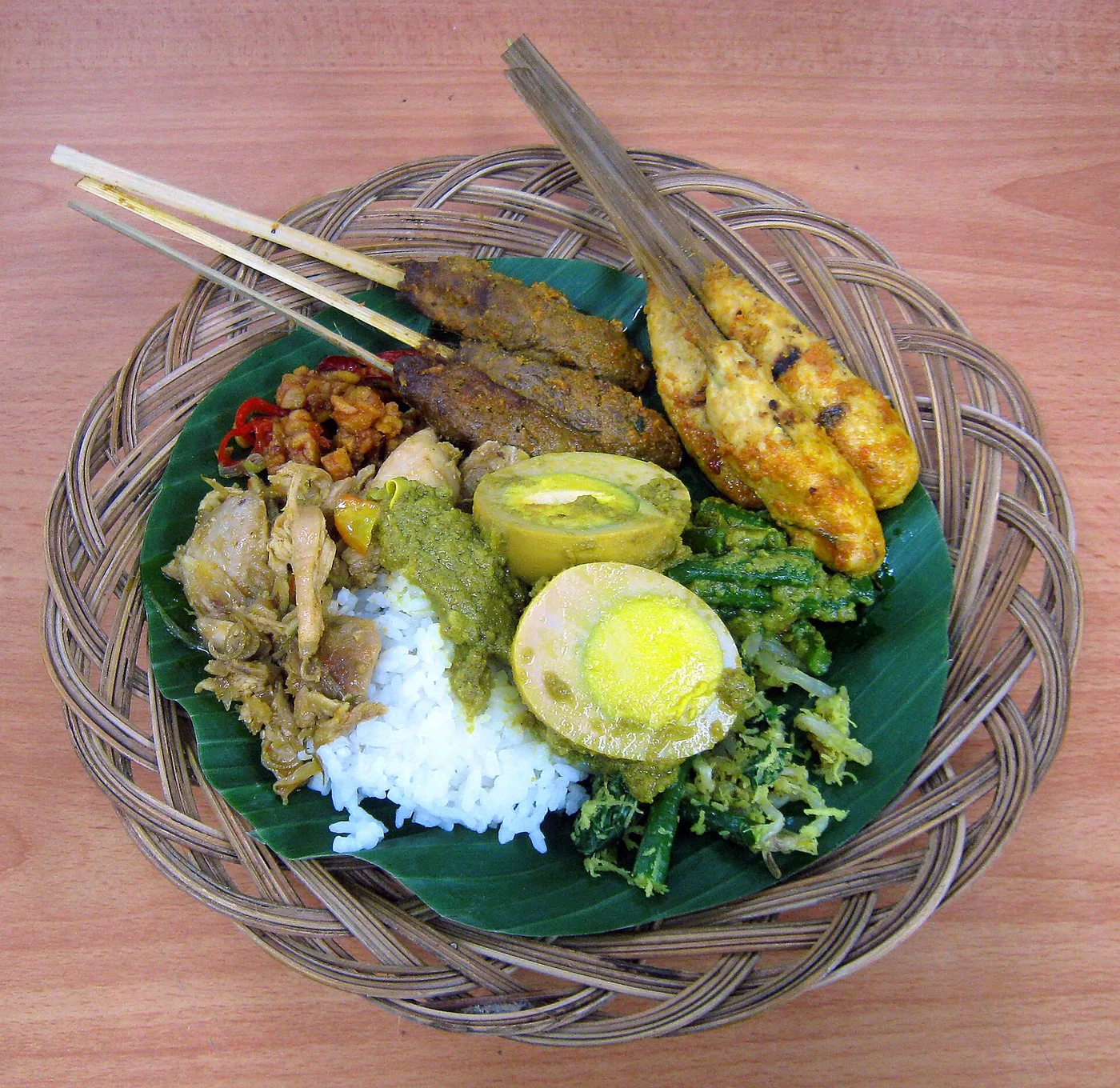 A Balinese nasi campur with sate lilit skewers on a banana leaf