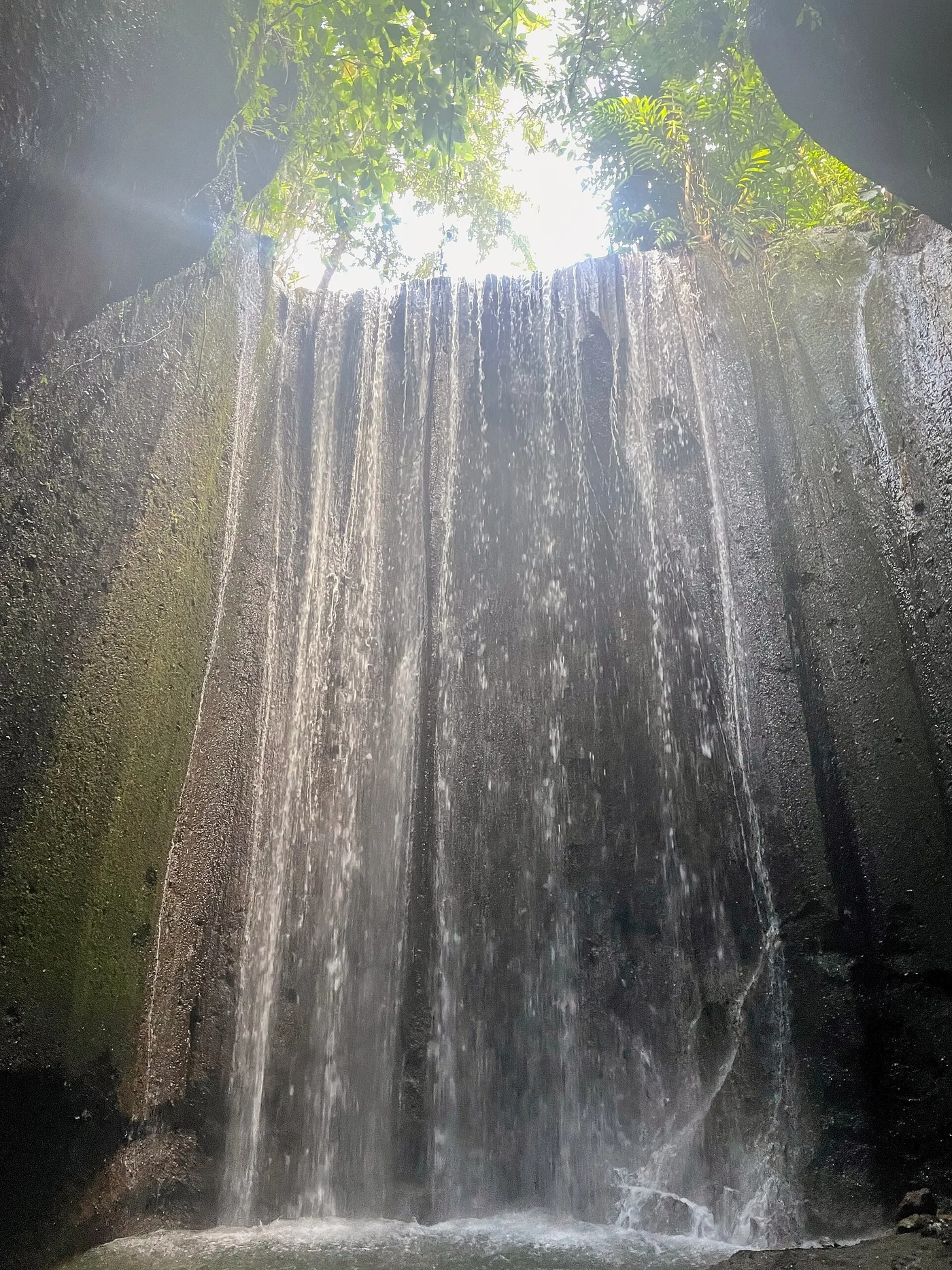 Daylight beaming through the canopy onto Tukad Cepung waterfall inside its slot canyon
