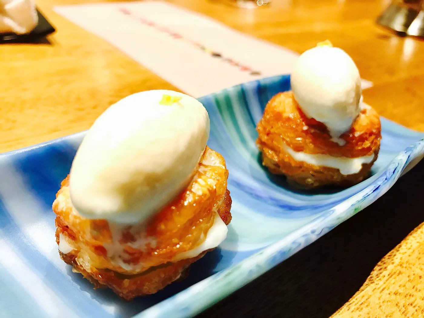 Two precisely plated dessert bites on a blue ceramic dish at Gaggan, Bangkok