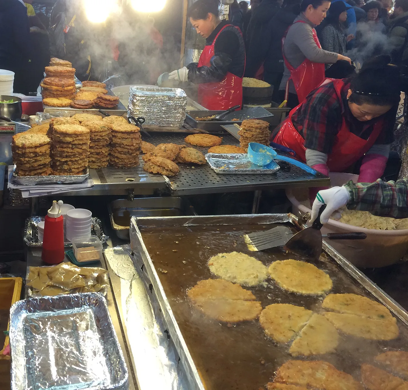Bindaetteok frying on a griddle at a Gwangjang Market stall