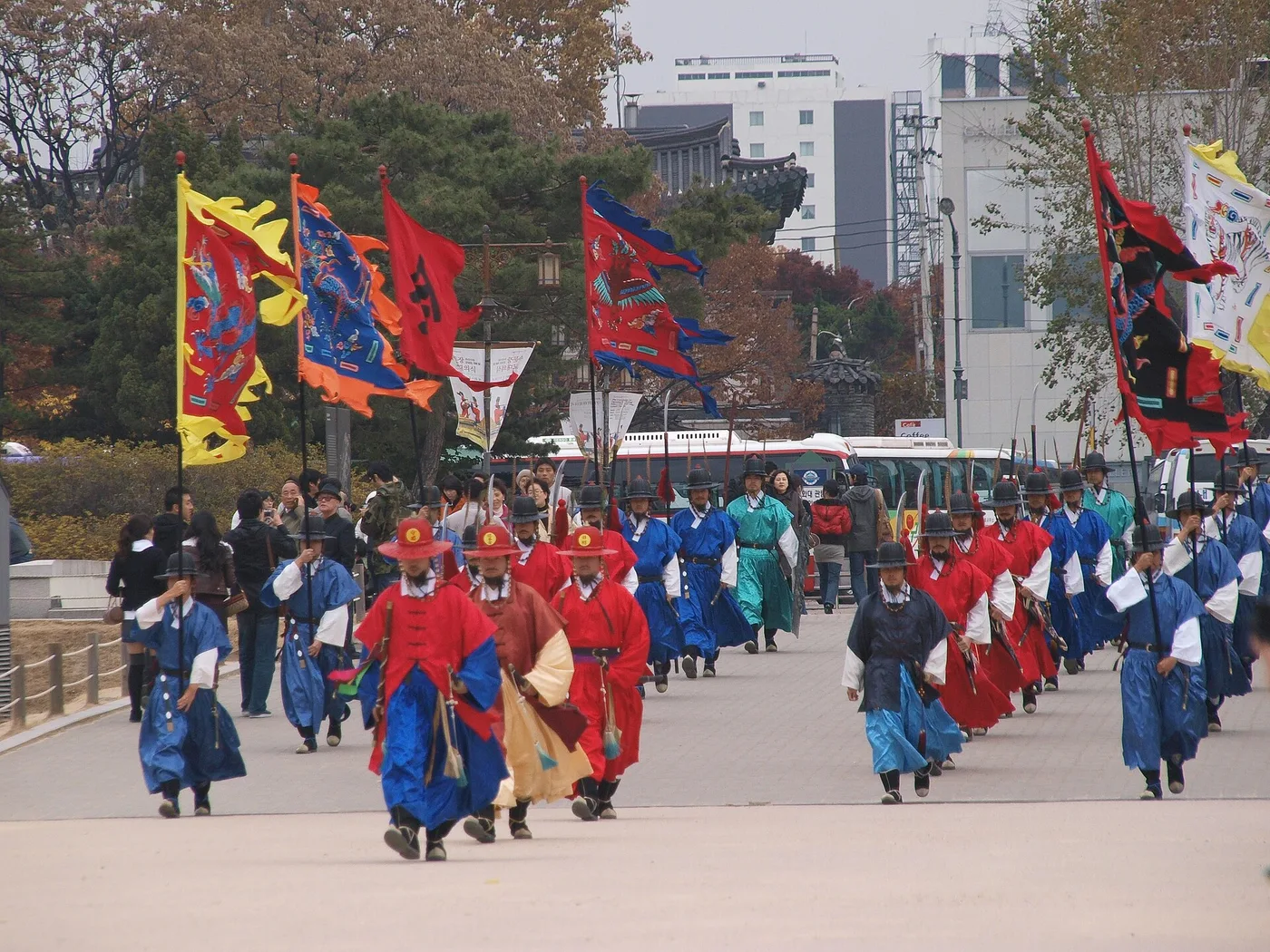 Palace guards in bright Joseon-era robes carrying banners at Gyeongbokgung