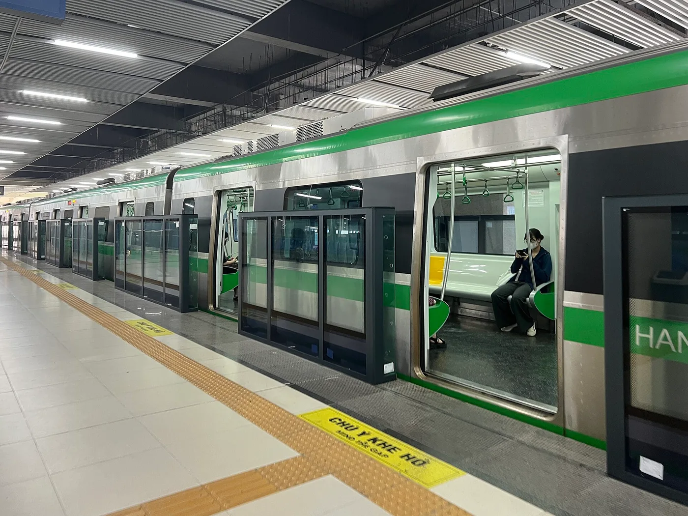 A green Hanoi Metro train at a station platform