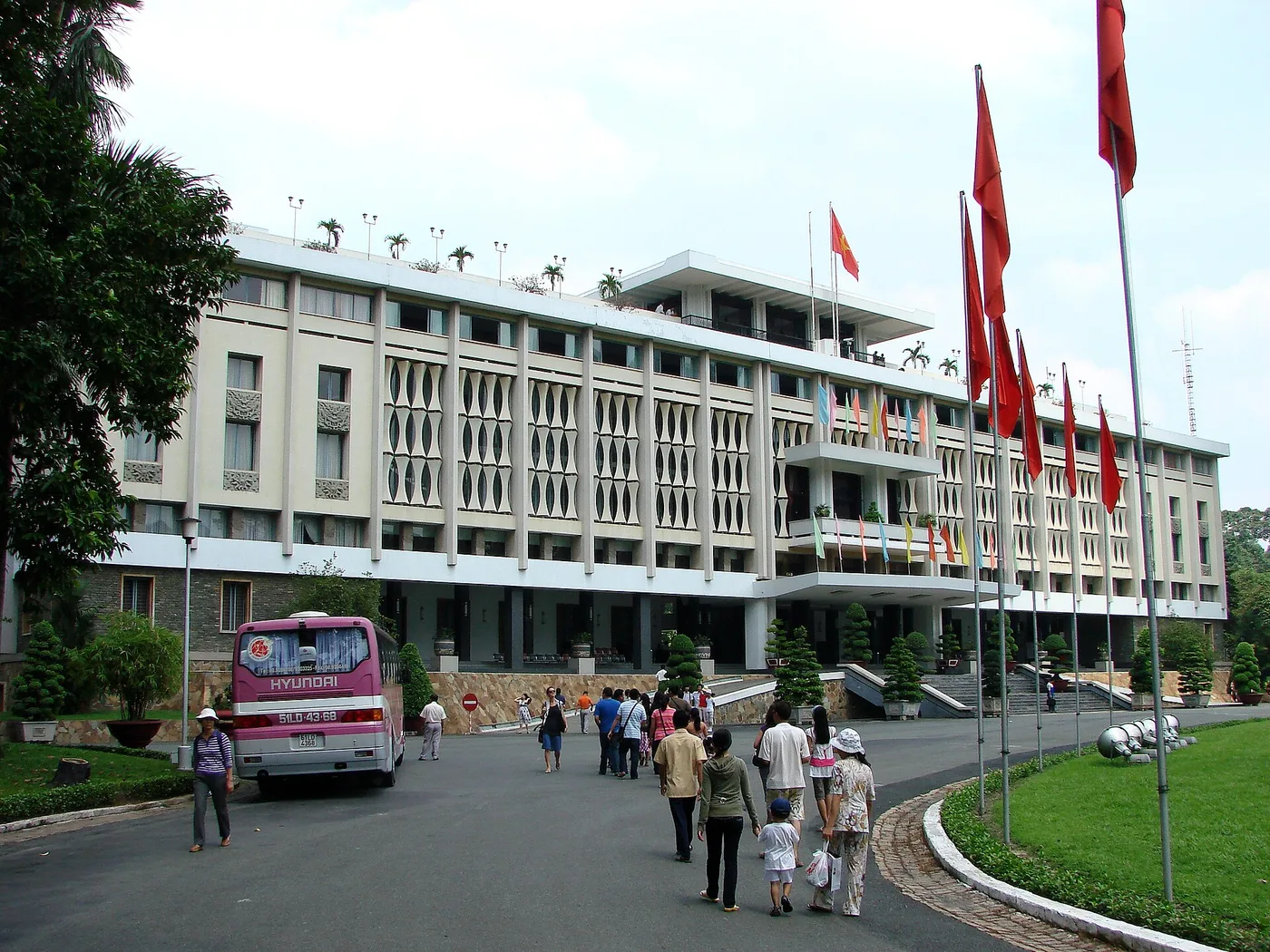 The modernist facade of Reunification Palace, flags lining its driveway
