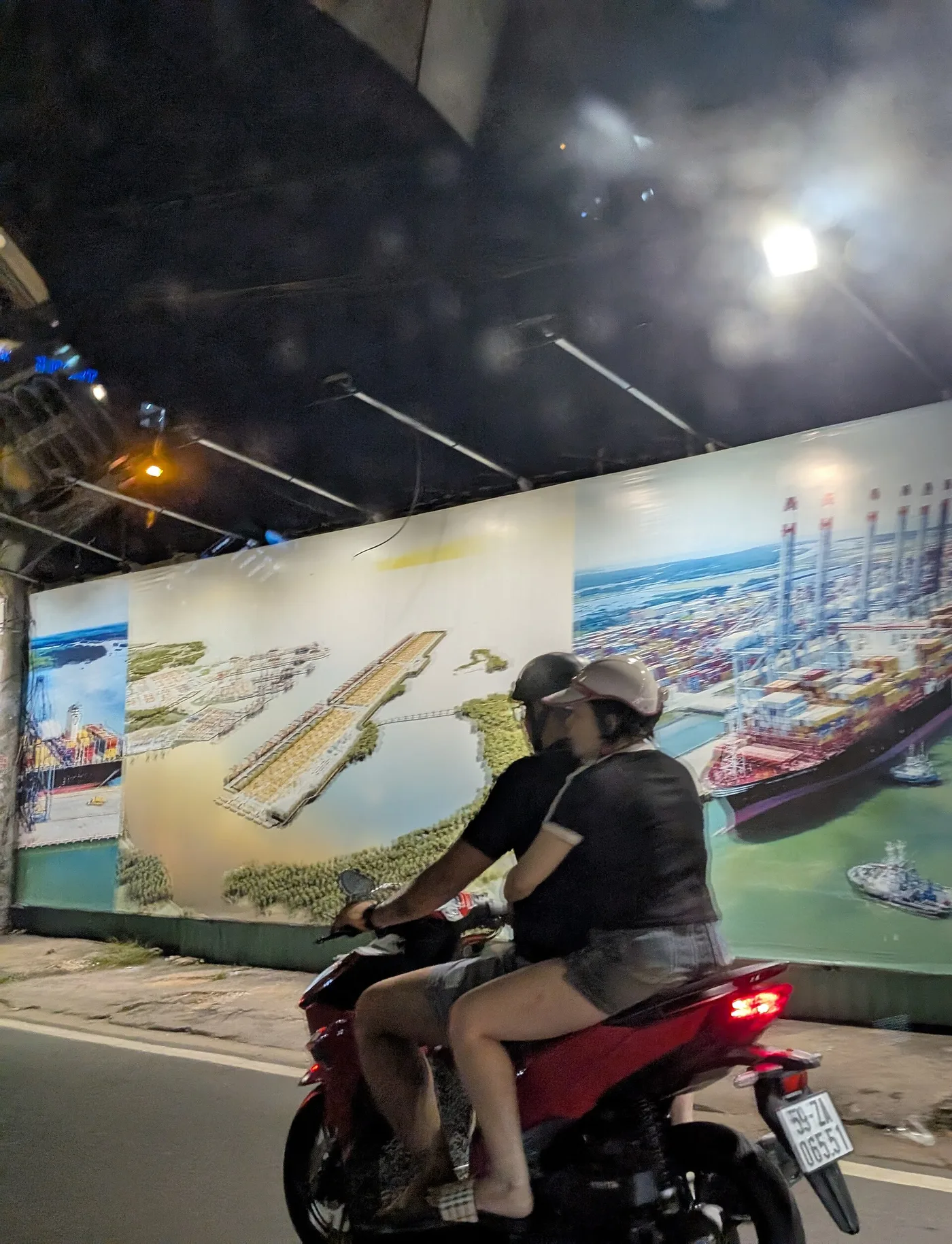 A couple riding two-up on a motorbike through a Saigon underpass at night