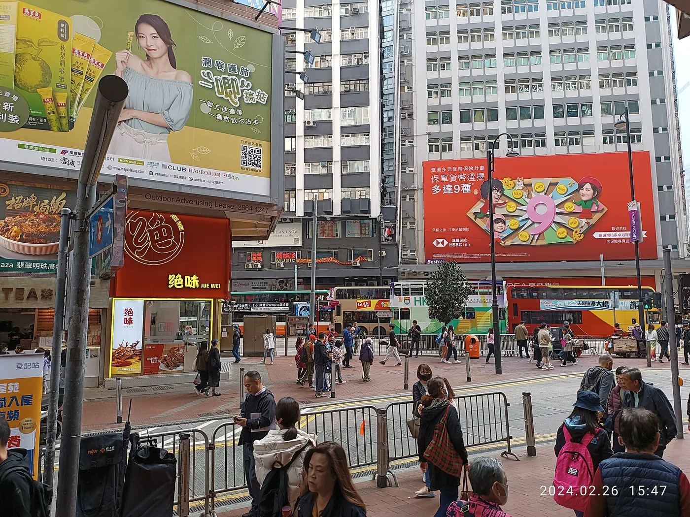 A busy Causeway Bay shopping street with billboards, trams and pedestrians