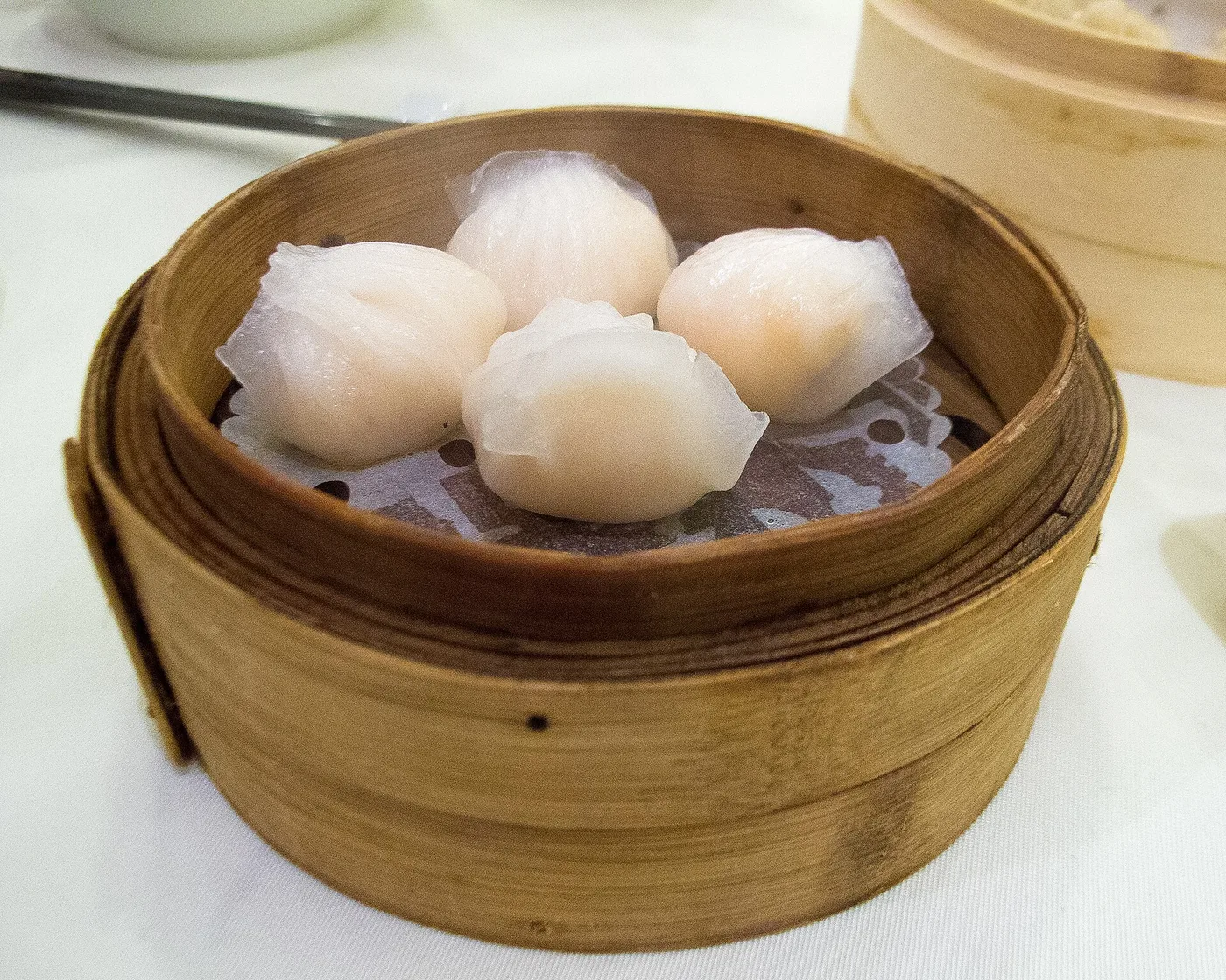 Four translucent har gow shrimp dumplings in a bamboo steamer