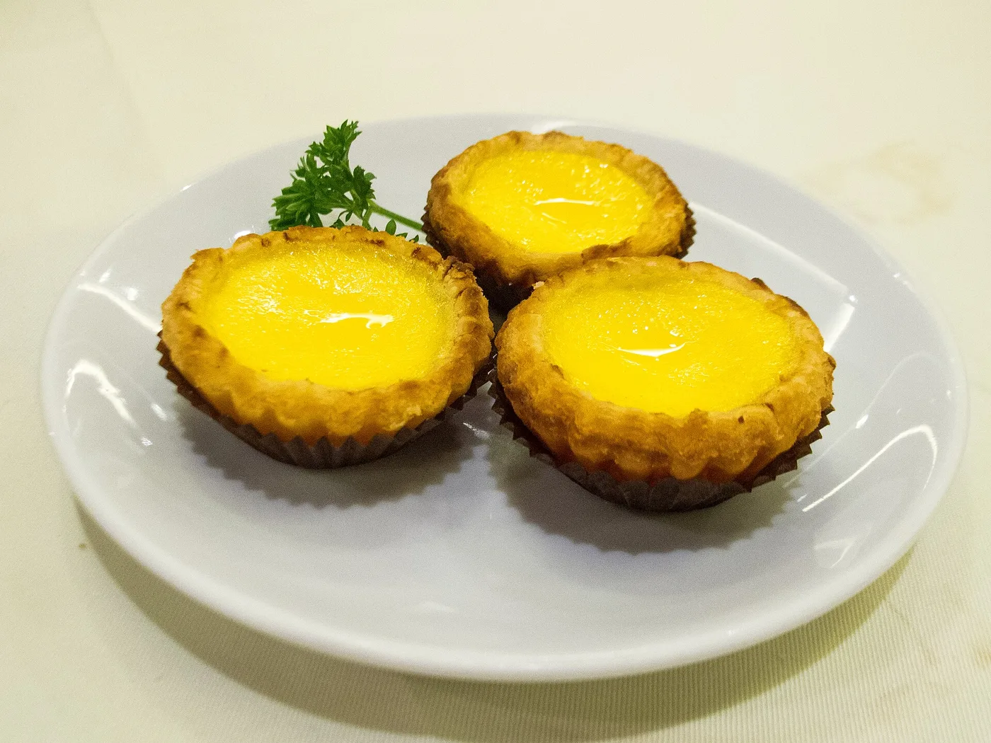 Three egg tarts with flaky pastry and a glossy custard centre