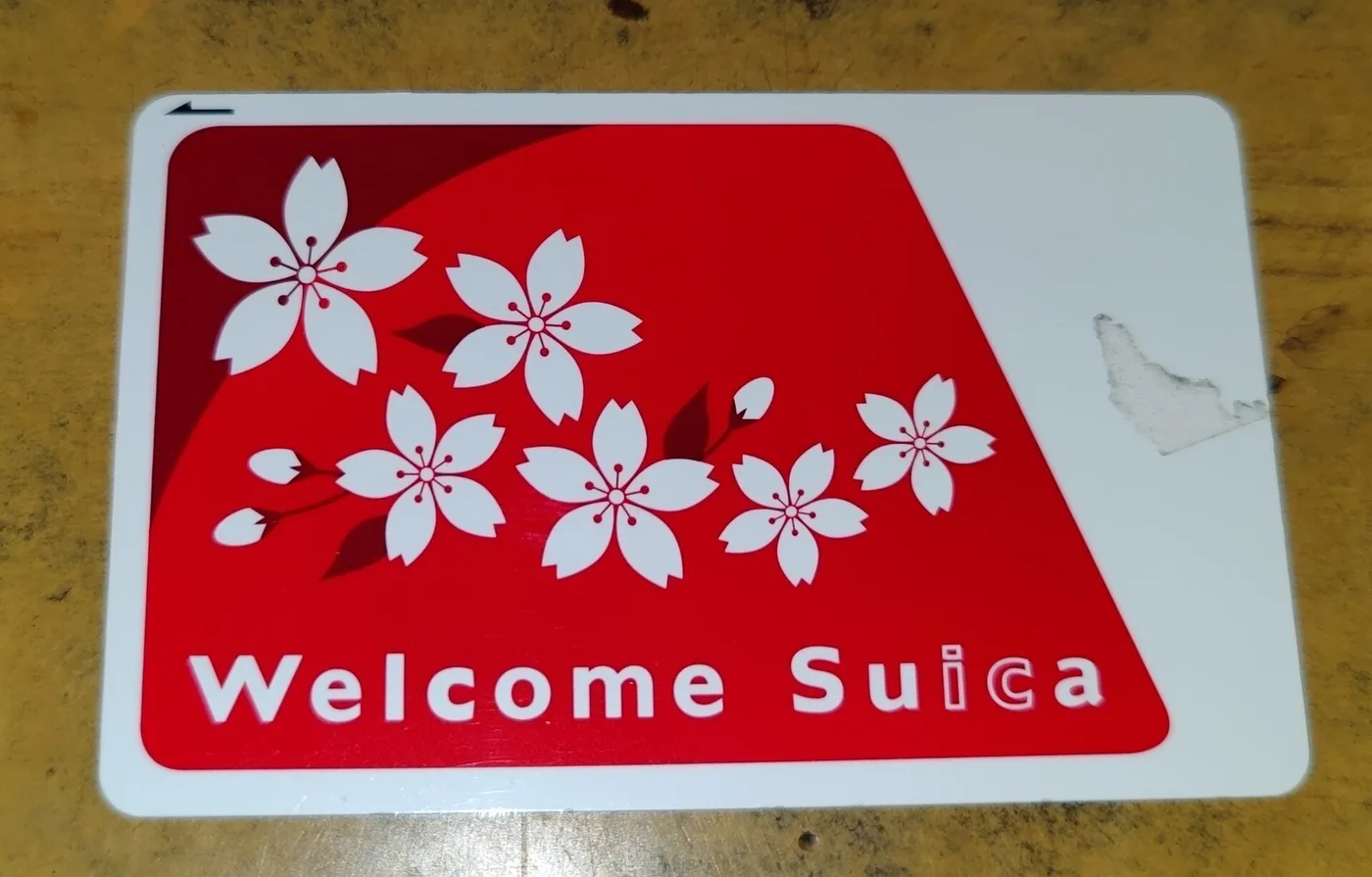 The red, cherry-blossom Welcome Suica card on a wooden table