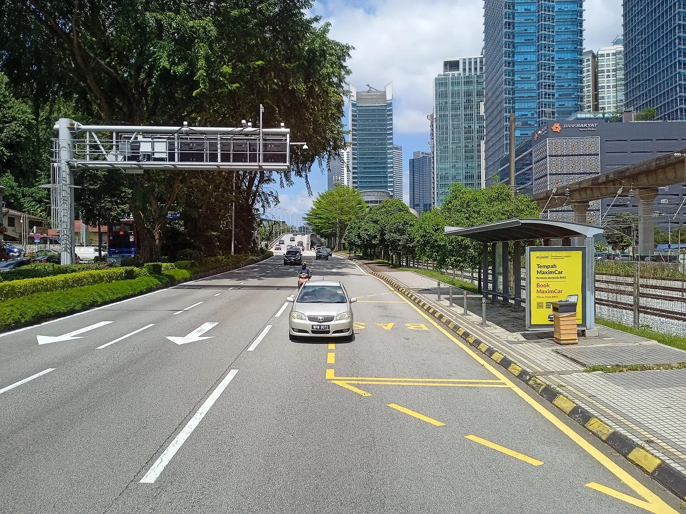 Jalan Bangsar, a tree-lined road with office towers and an elevated rail line behind