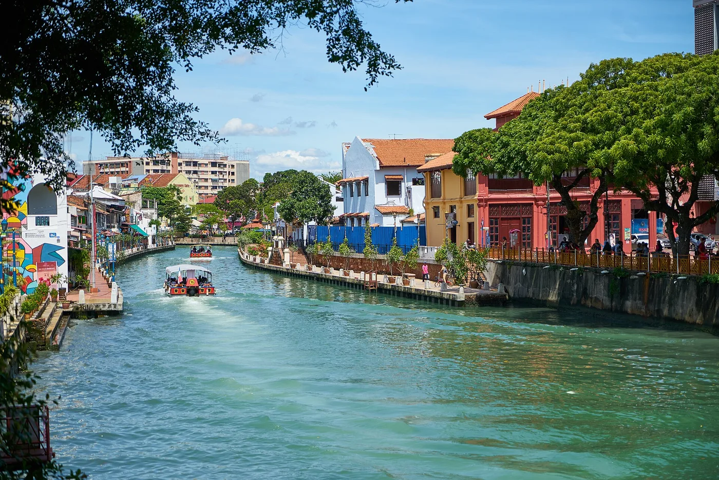 The Melaka River winding past painted riverfront shophouses, with a river-cruise boat