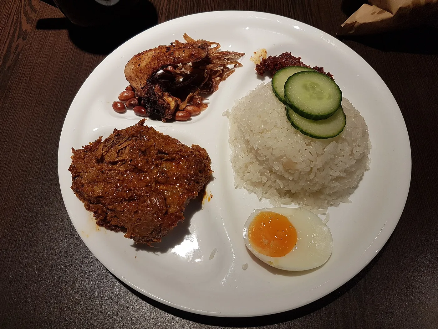 A plate of nasi lemak — coconut rice, rendang, sambal, fried anchovies, peanuts and a boiled egg