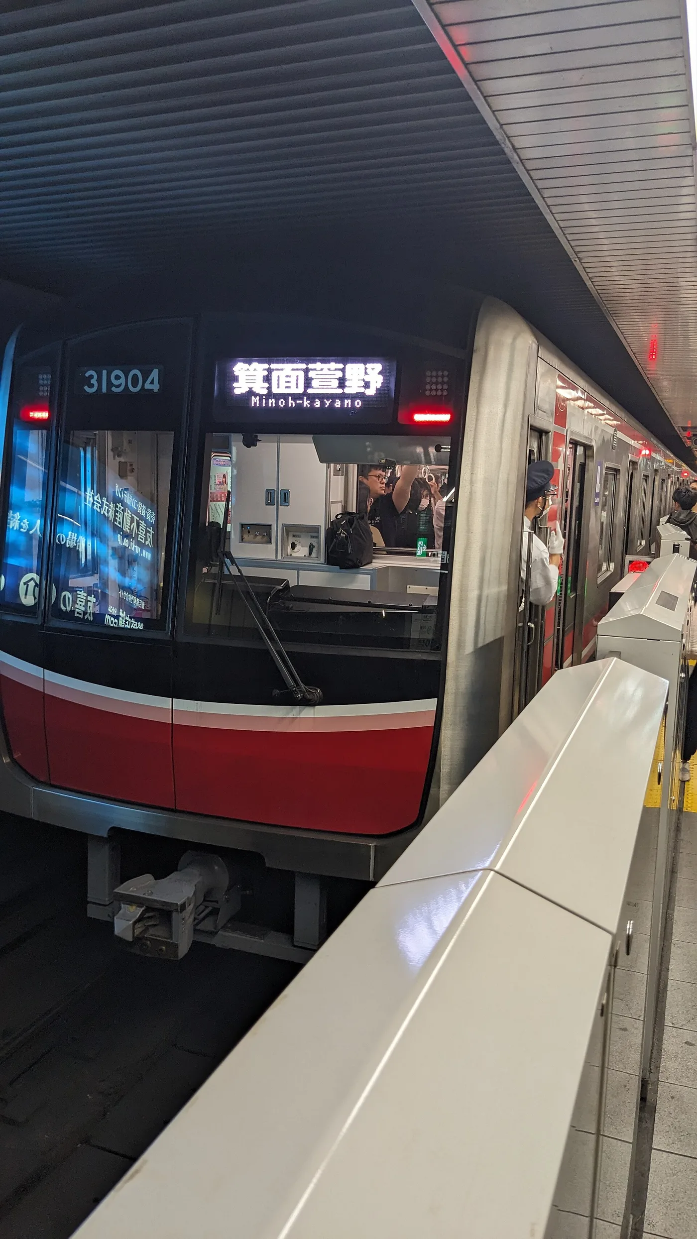 A red Osaka Metro Midōsuji-line train at a platform