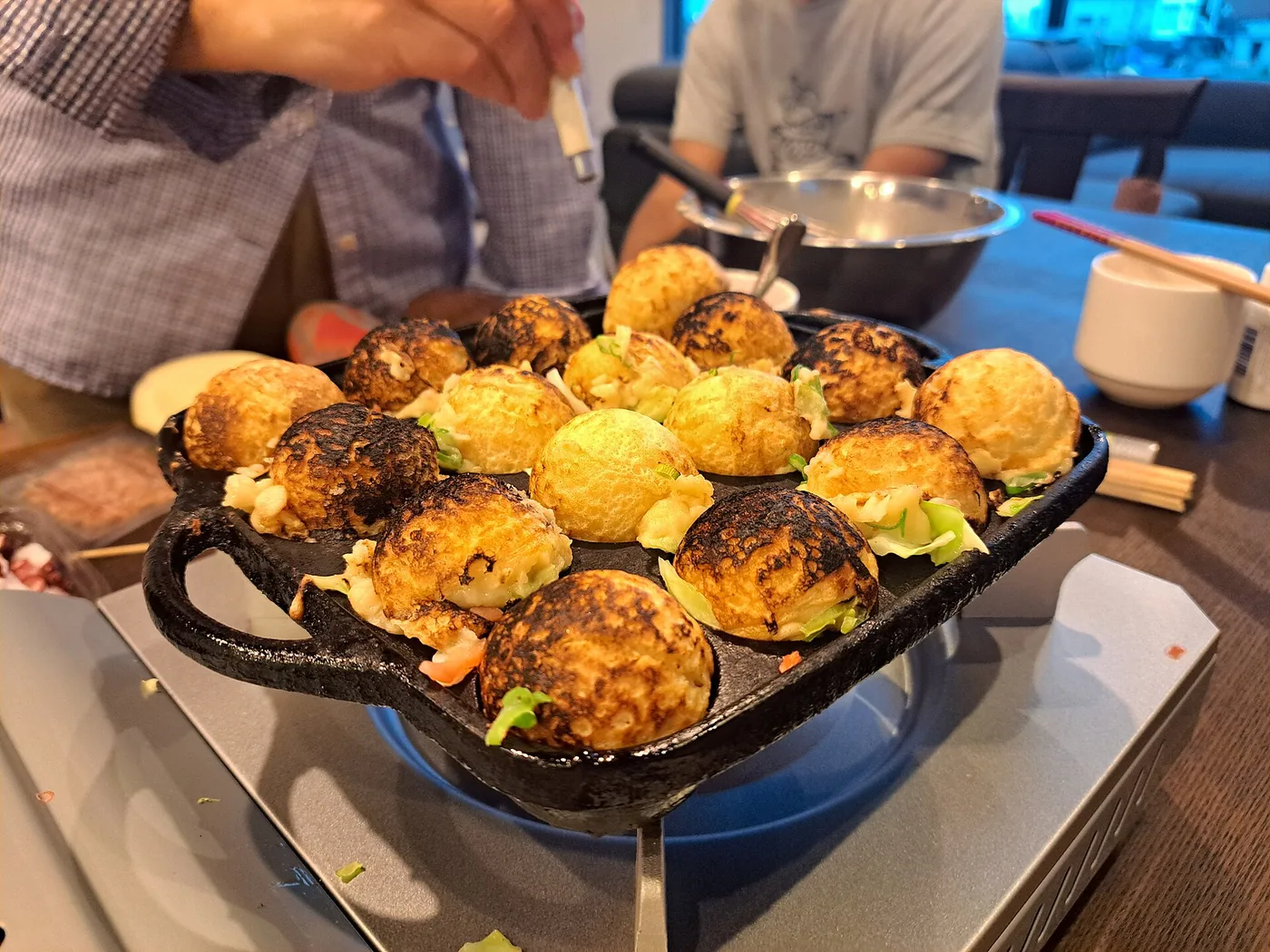 Takoyaki browning in a dimpled cast-iron griddle