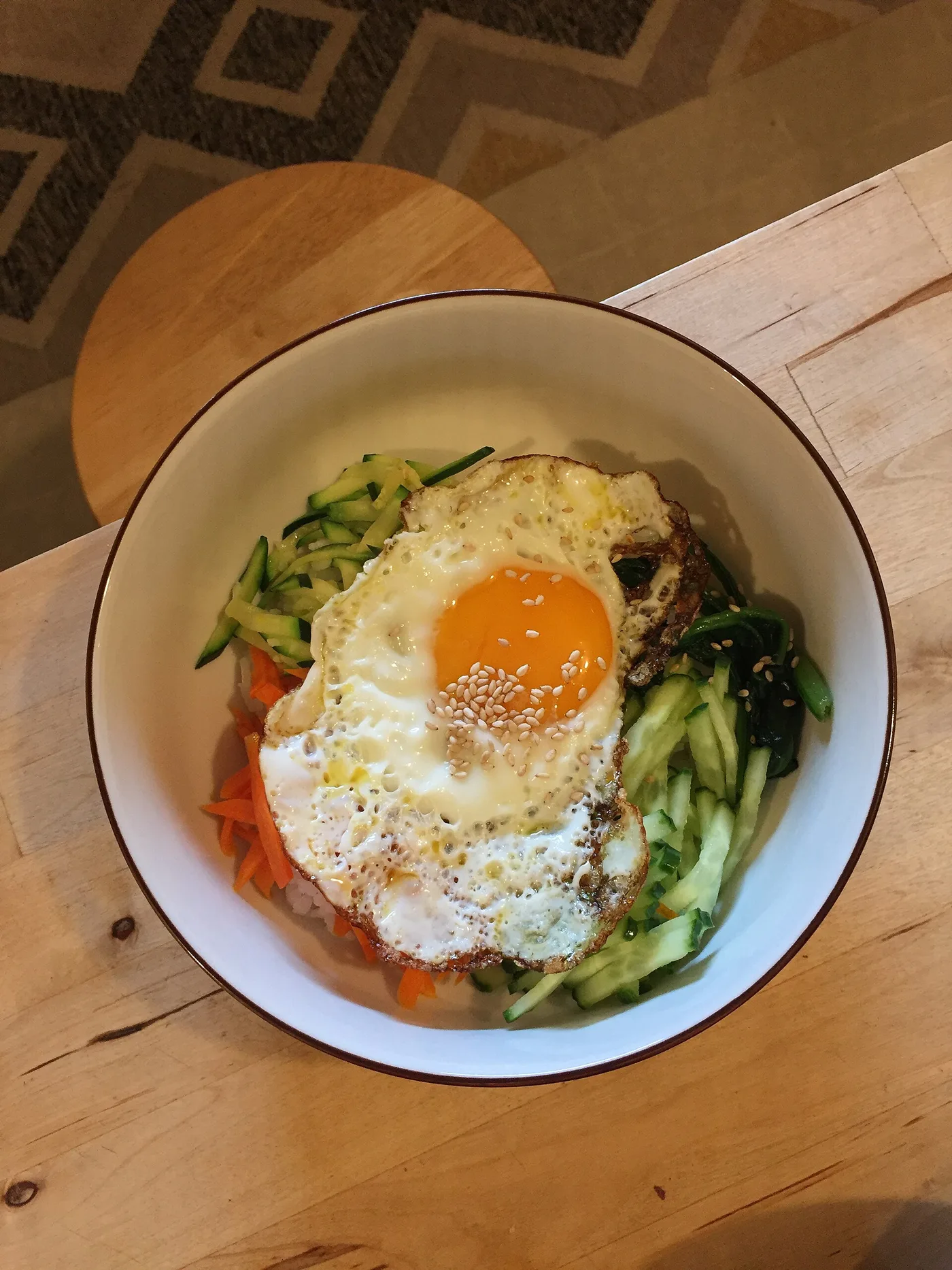 A bowl of bibimbap topped with julienned vegetables and a fried egg