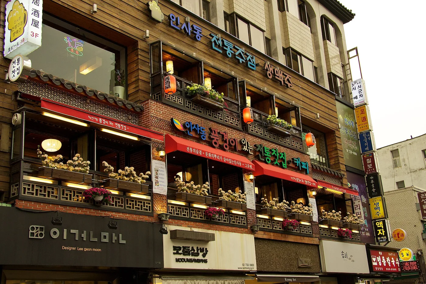 A traditional-style teahouse facade on an Insadong street, red lanterns and shop signs