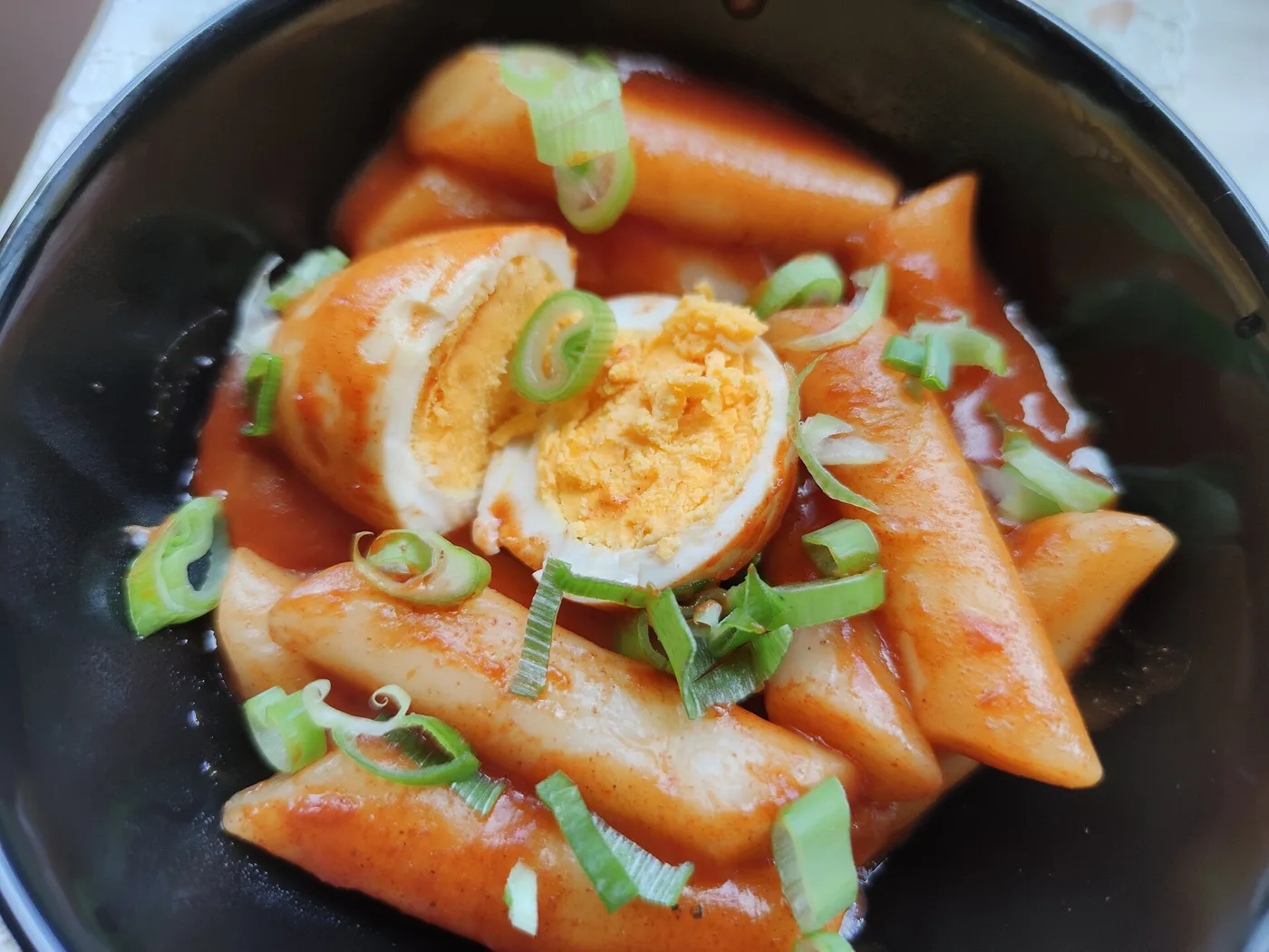 A bowl of tteokbokki rice cakes in red sauce