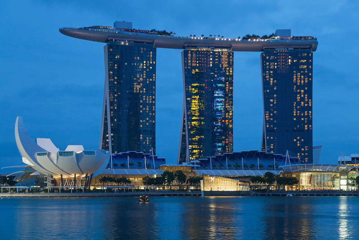 Marina Bay Sands' three towers and boat-shaped rooftop SkyPark, lit up across the bay at dusk