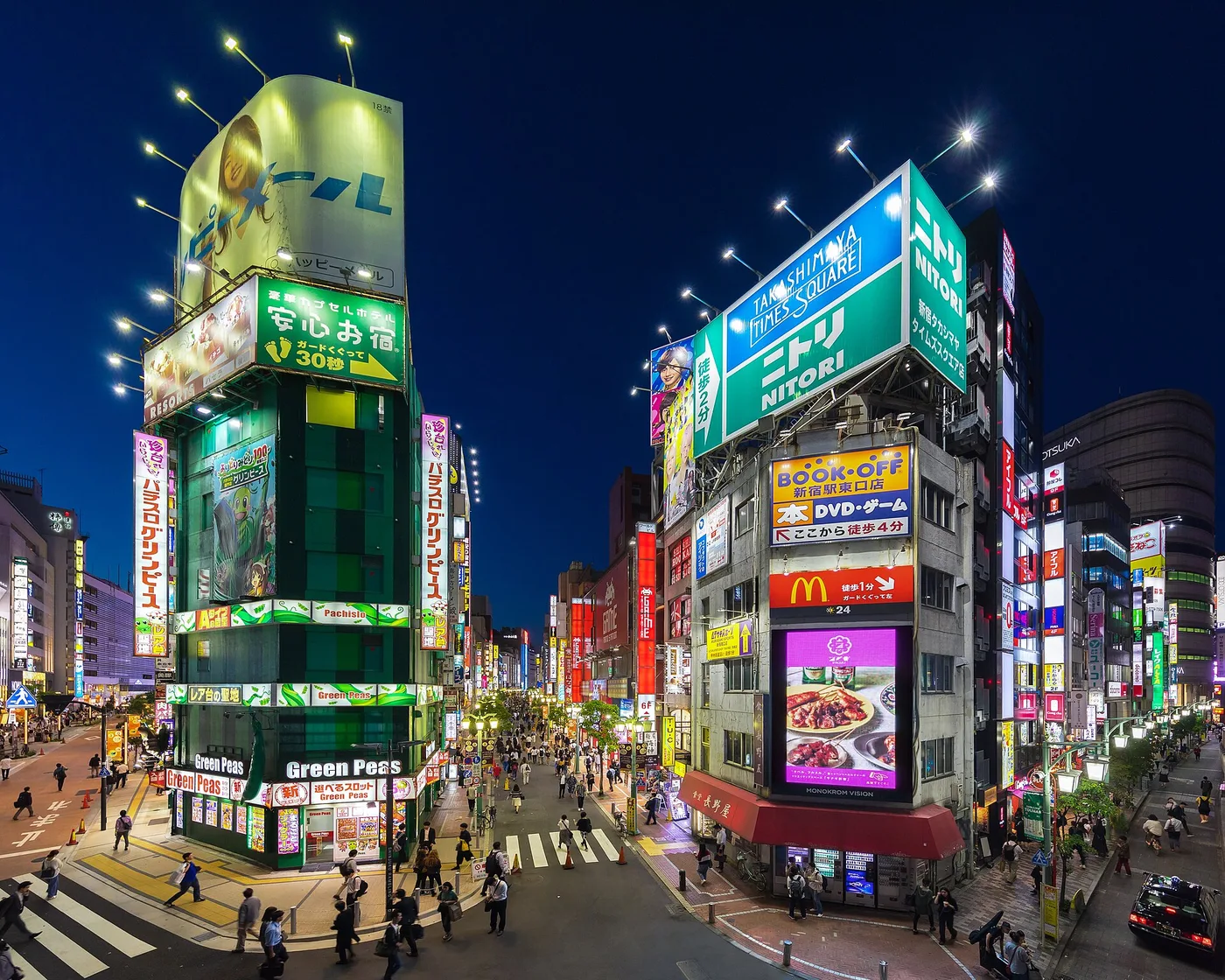 Neon-covered buildings and crowds outside Shinjuku Station at dusk