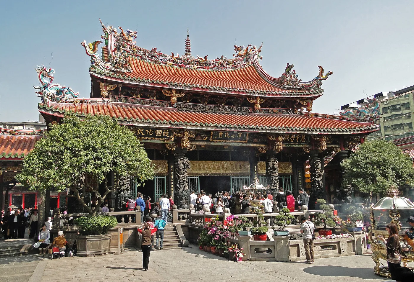 The ornate main hall of Longshan Temple in Taipei, with worshippers in the courtyard