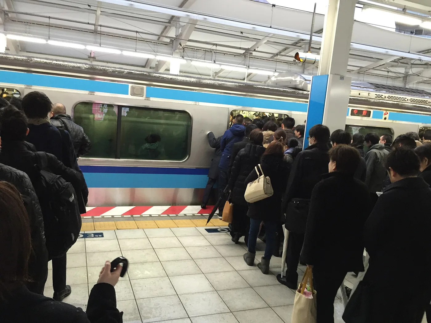 Morning commuters crowding onto a Tokyo Metro train at rush hour